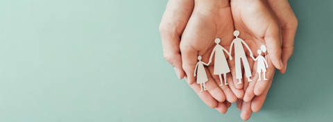Hands holding paper cut out of family on blue background 